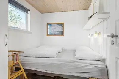 a bed in a room with white walls and a window at BL789-Blokhus-Pirupshvarrevej-20 in Blokhus