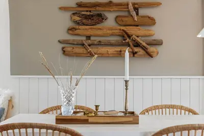 a dining room with a table with chairs and a shelf with logs at BL1640-Blokhus-Solbakkevej-2 in Blokhus