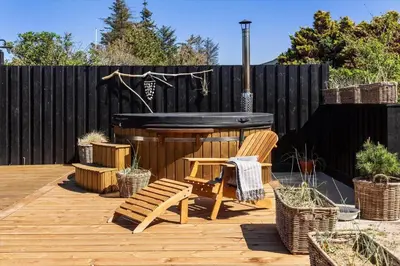a backyard with a hot tub and a wooden deck at BL1640-Blokhus-Solbakkevej-2 in Blokhus