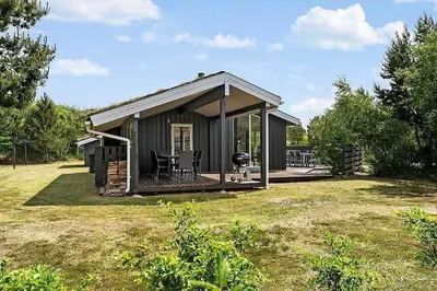 a small cabin with a deck and a grill at BL257-Pandrup-Rodhus-Skolevej-44 in Pandrup
