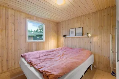 a bedroom with a bed in a wooden wall at BL762-Blokhus-Berberisvej-49 in Blokhus
