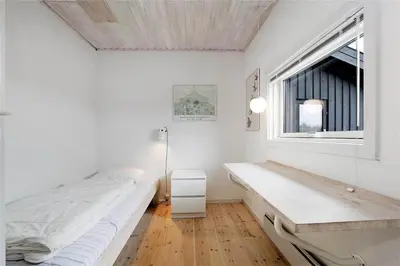 a white bedroom with a bed and a window at BL358-Pandrup-Kaskelotten-5 in Pandrup