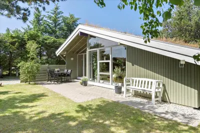a green house with a white bench on a patio at BL609-Pandrup-Rodhus-Skolevej-10 in Pandrup