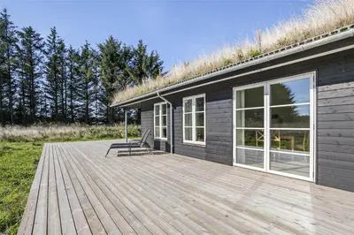 a wooden deck with a house with a grass roof at BL386-Saltum-Nordvestvej-13 in Saltum