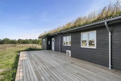 a black house with a grass roof with a wooden deck at BL386-Saltum-Nordvestvej-13 in Saltum