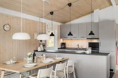 a kitchen with a long table with chairs and lights at BL103-Saltum-Daadyrvej-23-A in Saltum
