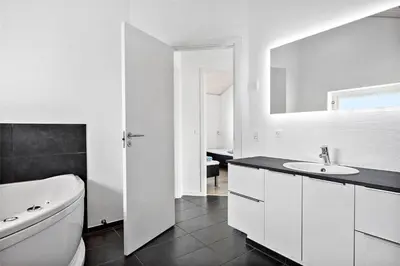 a white bathroom with a sink and a mirror at BL417-Blokhus-Saetergaardsstien-6-A in Blokhus