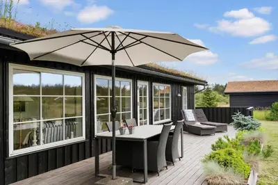 a patio with a table and an umbrella on a deck at BL653-Saltum-Nordvestvej-27 in Saltum