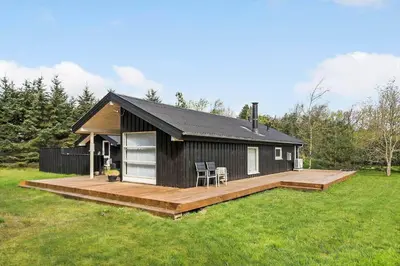 a small black cabin with a wooden deck at BL1739-Blokhus-Bag-Hojen-47 in Blokhus
