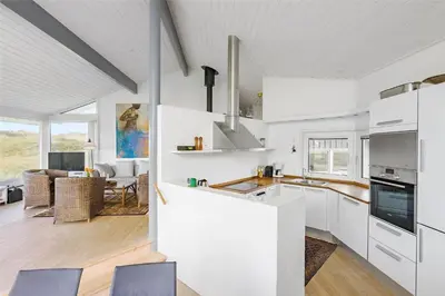 a kitchen with white cabinets and a living room at BL1555-Blokhus-Egebaeksvej-17 in Blokhus