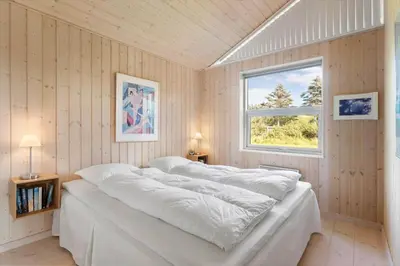 a bedroom with a large white bed with a window at BL935-Blokhus-Tobaksvej-1 in Blokhus