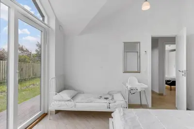 a white bedroom with a bed and a large window at BL234-Blokhus-Sdr-Strandvej-9-A in Blokhus