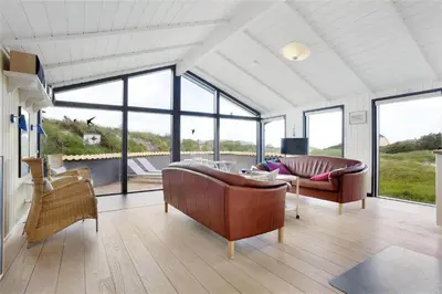 a living room with a couch and chairs and windows at BL441-Pandrup-Sydvej-14 in Pandrup