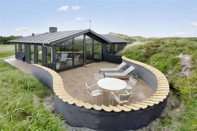 a house on the beach with a table and chairs at BL441-Pandrup-Sydvej-14 in Pandrup