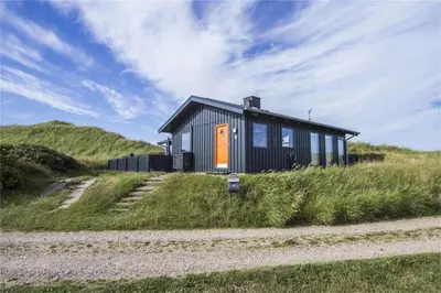 a black and orange house on a hill with a gravel road at BL441-Pandrup-Sydvej-14 in Pandrup