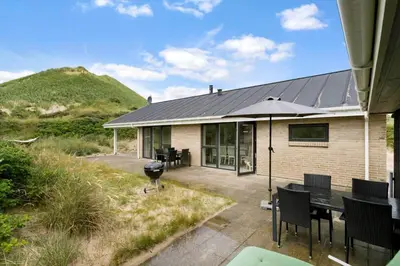 a house with a patio with a table and an umbrella at BL1660-Saltum-Hvide-Klit-7 in Saltum