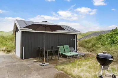 a patio with a table and an umbrella and a grill at BL1660-Saltum-Hvide-Klit-7 in Saltum