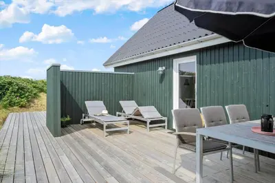 a deck with chairs and a table and a building at BL1580-Saltum-Kohlsvej-17 in Saltum