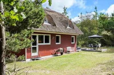 a red house with a porch and a patio at BL238-Pandrup-Fyrregangen-18 in Pandrup
