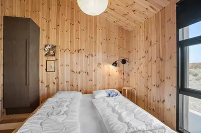 a bedroom with a bed in a wooden wall at BL1436-Blokhus-Mollevej-13 in Blokhus