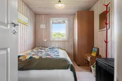 a small bedroom with a bed and a window at BL1211-Blokhus-Carl-Nielsensvej-3 in Blokhus