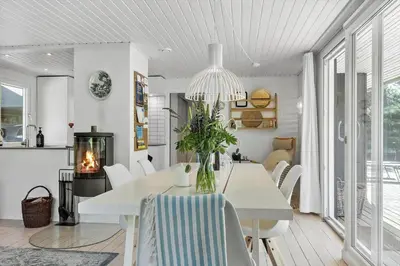 a white dining room with a table and a fireplace at BL1585-Blokhus-Bregnehojvej-1 in Blokhus
