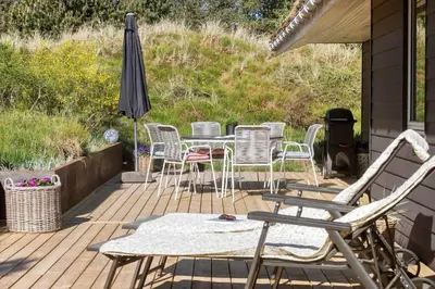 a deck with a table and chairs and an umbrella at BL1585-Blokhus-Bregnehojvej-1 in Blokhus