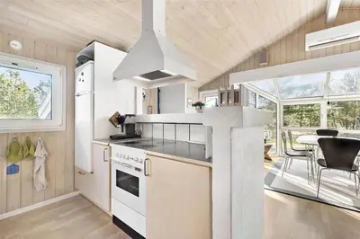 a kitchen with white appliances and a table with chairs at BL1186-Blokhus-Morten-Nielsensvej-84 in Blokhus