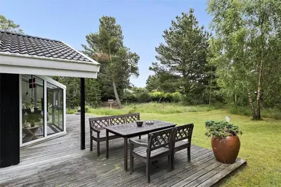 a wooden deck with a table and chairs on it at BL1186-Blokhus-Morten-Nielsensvej-84 in Blokhus