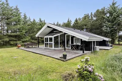 a house with a wooden deck in a field at BL1186-Blokhus-Morten-Nielsensvej-84 in Blokhus