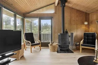a living room with a fireplace and a flat screen tv at BL1714-Saltum-Lyngsletten-11 in Saltum