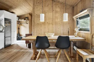 a kitchen with a wooden table and black chairs at BL1714-Saltum-Lyngsletten-11 in Saltum