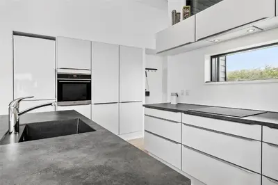 a kitchen with white cabinets and a sink and a window at BL1651-Blokhus-Pirupshvarrevej-21 in Blokhus