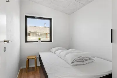 a white bedroom with a bed and a window at BL1651-Blokhus-Pirupshvarrevej-21 in Blokhus