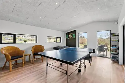 a ping pong table in a room with chairs at BL1651-Blokhus-Pirupshvarrevej-21 in Blokhus