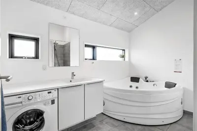 a white bathroom with a washing machine and a sink at BL1651-Blokhus-Pirupshvarrevej-21 in Blokhus