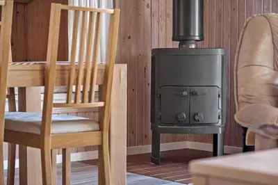 a wood stove in a living room with a chair and a fireplace at BL286-Blokhus-Bag-Hojen-31 in Blokhus