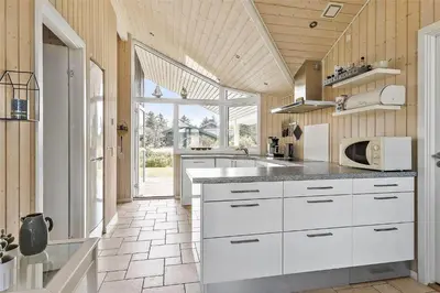 a kitchen with white cabinets and a large window at BL1139-Blokhus-Sletten-3 in Blokhus