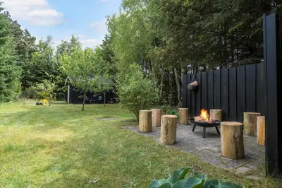 a fire pit in a yard with wooden stools at BL1247-Blokhus-Skraavejen-24 in Blokhus
