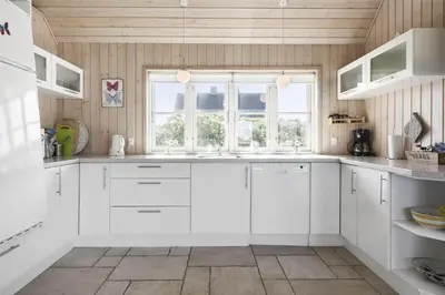 a kitchen with white cabinets and a window at BL1357-Blokhus-Ved-Stranden-2 in Blokhus
