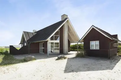 a house with a black roof on a beach at BL1357-Blokhus-Ved-Stranden-2 in Blokhus