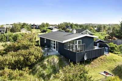 a black house sitting on top of a field at BL374-Blokhus-Vagerfedet-10 in Blokhus