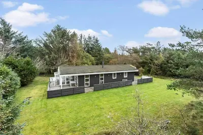 a black house in a field with a yard at BL1213-Pandrup-Rodhusparken-14 in Pandrup
