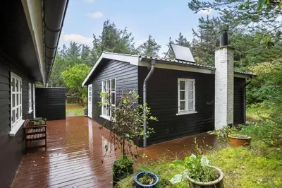 a small black house with a wooden deck at BL554-Blokhus-Kragebak-2 in Blokhus