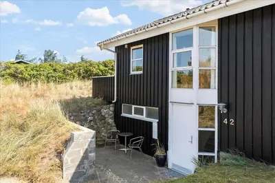 a black house with a white door and a table at BL362-Blokhus-Klitvejen-42 in Blokhus