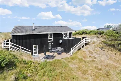 a black house sitting on top of a beach at BL362-Blokhus-Klitvejen-42 in Blokhus