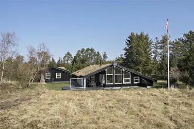 a black house on top of a field at BL464-Blokhus-Blaabaerskraenten-8 in Blokhus
