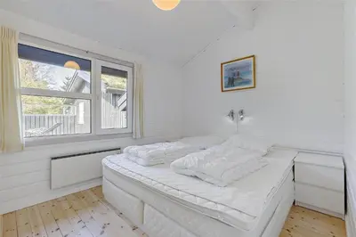 a white bedroom with a bed and a window at BL464-Blokhus-Blaabaerskraenten-8 in Blokhus