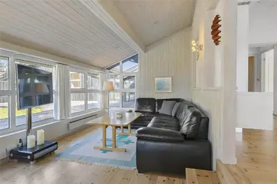 a living room with a black leather couch and a table at BL464-Blokhus-Blaabaerskraenten-8 in Blokhus