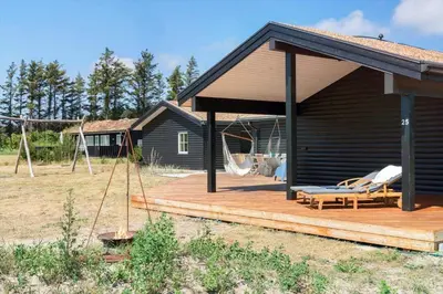 a cabin with a wooden deck with a porch at BL1559-Saltum-Nordvestvej-25 in Saltum